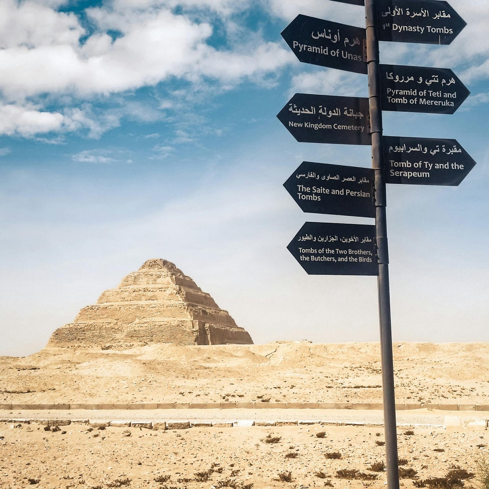 Signpost near the Pyramid of Djoser in the Egyptian desert, clear blue sky.