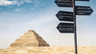 Signpost near the Pyramid of Djoser in the Egyptian desert, clear blue sky.