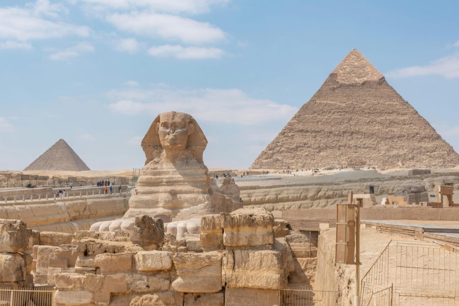 Iconic view of the Great Sphinx and Giza Pyramids in Egypt under a clear blue sky.
