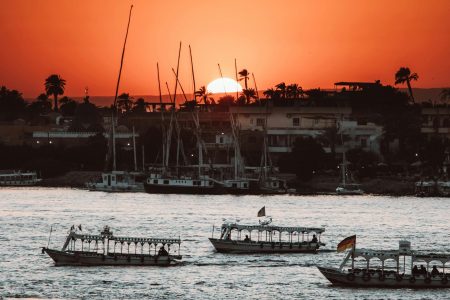 Serene sunset view of boats sailing on the Nile River in Luxor, Egypt.