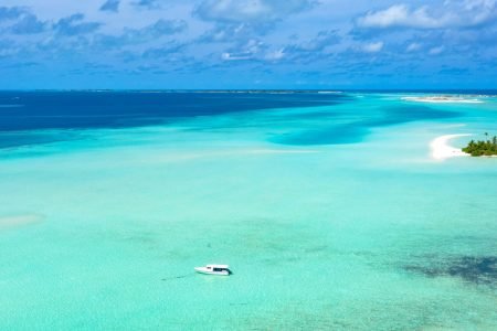A serene aerial view showcasing turquoise waters and a remote island in the Maldives.